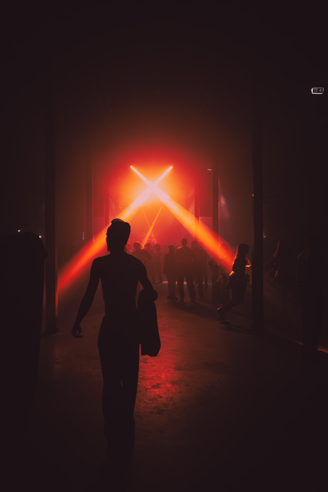 A lone figure walking towards a red cross of light in the fog